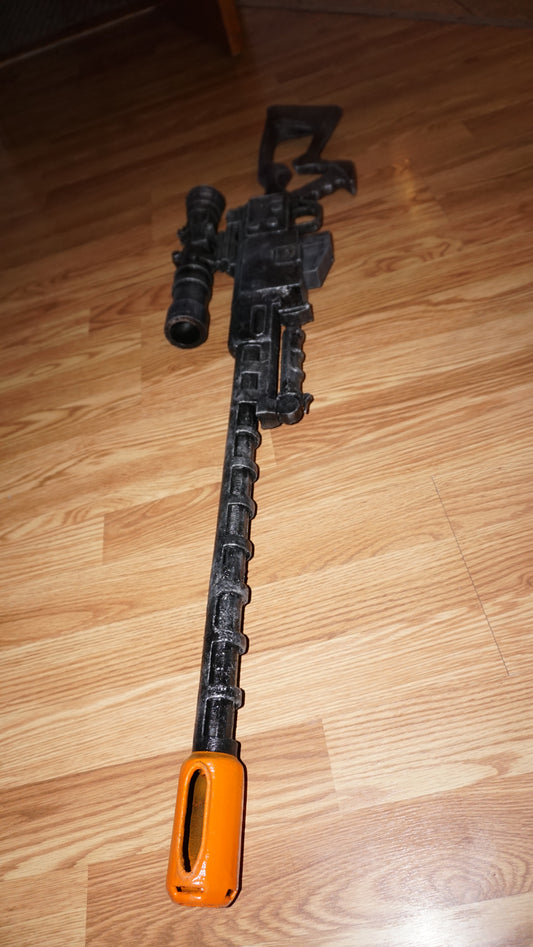 A black toy gun with an orange muzzle is lying on a wooden floor.