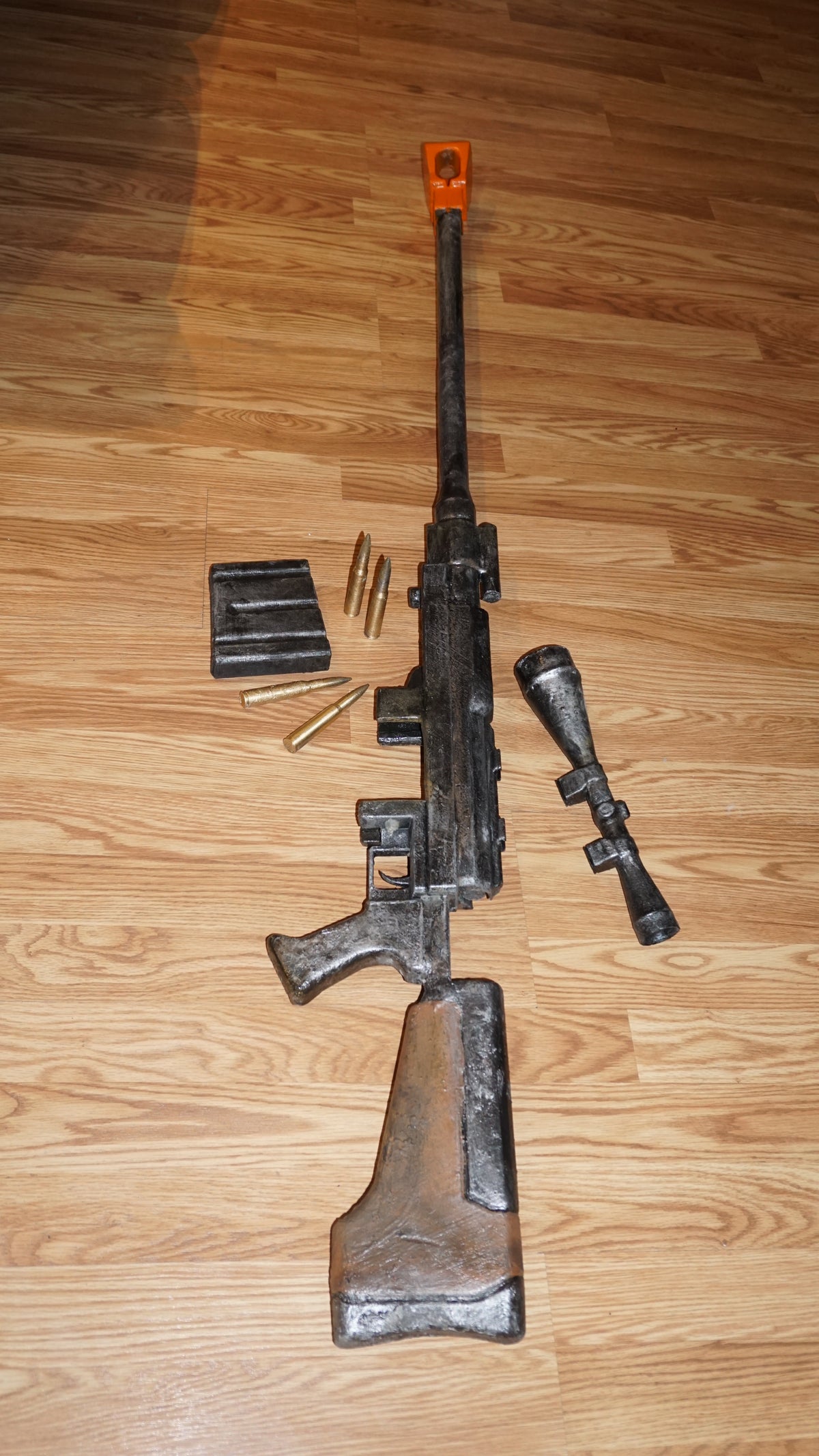 a toy gun with a scope and a toy bullet on a wooden floor.