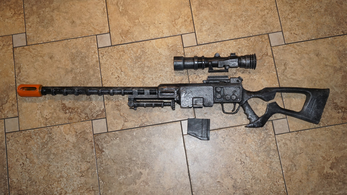 A toy gun with a scope and flash is lying on a tiled floor.