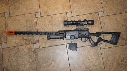 A toy gun with a scope and flash is lying on a tiled floor.