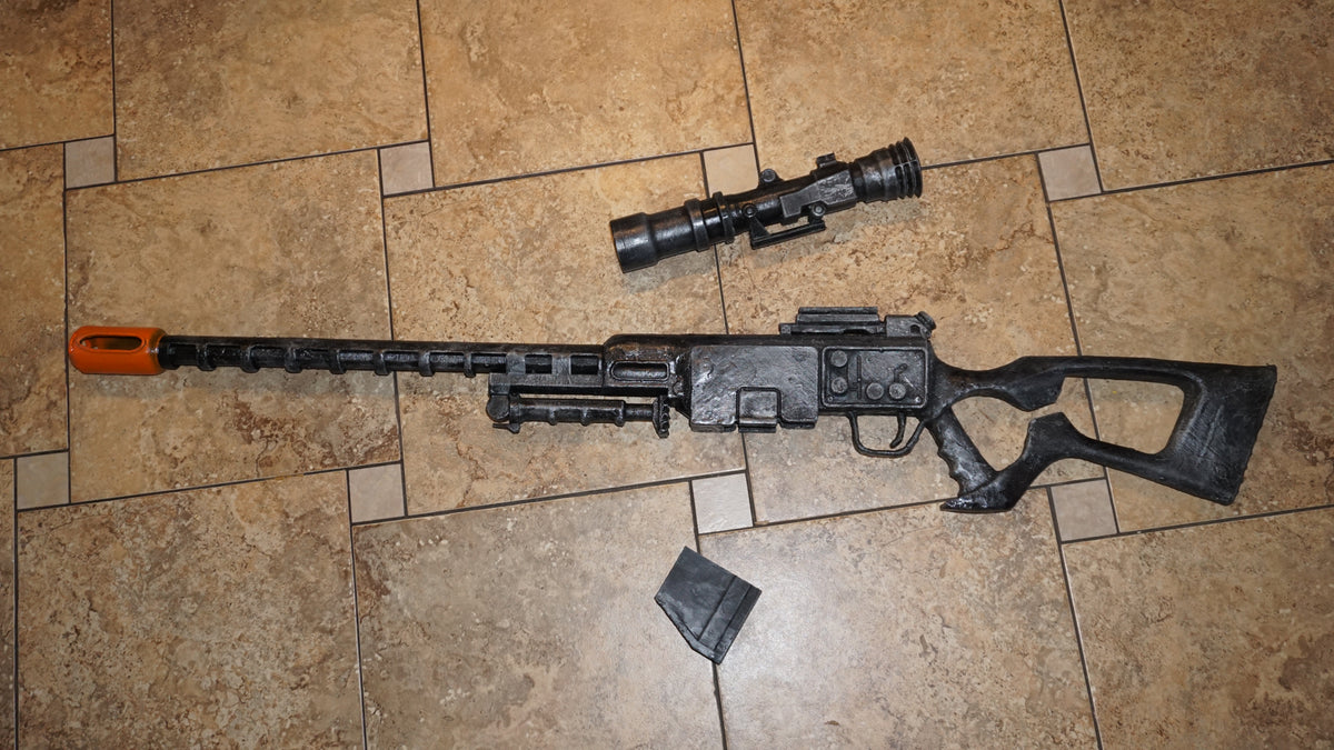 A toy gun with a scope and a flash attachment is lying on a tiled floor.